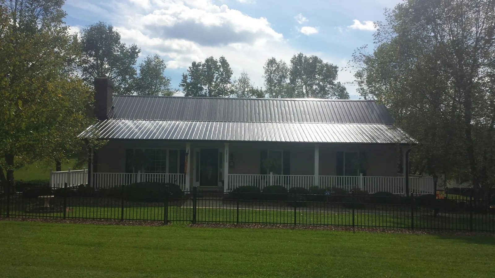 Gray metal roof on a brick ranch with a full width front porch — Gutter Guard Installation work by our crew in Arriba